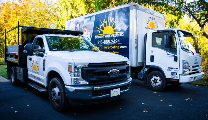 Jamison Basement Waterproofing service trucks parked outside residential property