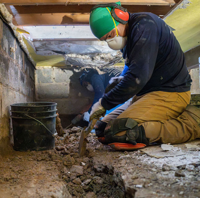 Workers digging trench in confined crawlspace